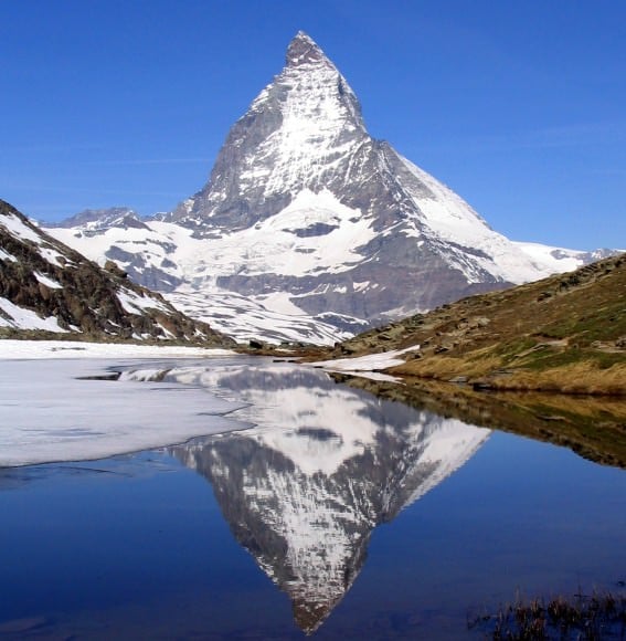 Matterhorn (4,478 m, Walliser Alps, East side) mirrored in Riffelsee, photograph taken from shore of lake Riffelsee.