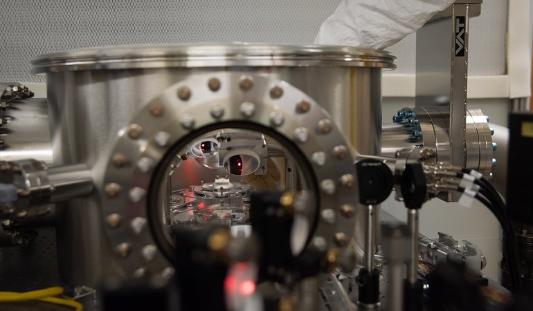 One of the coated pieces of glass in a test chamber with a red laser beam.