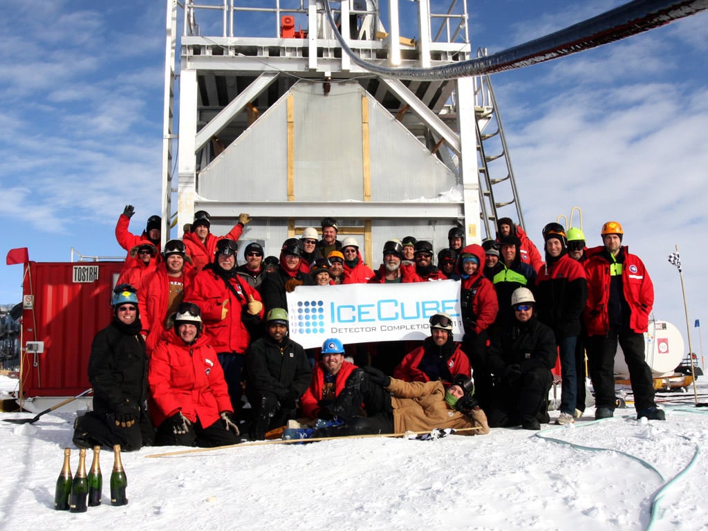 IceCube team poses for a picture in front of deployment tower after the completion of the IceCube Neutrino Detector in December of 2010.