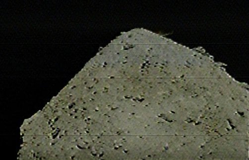 DCAM 3 captured this image of the SCI impact on 5 April 2019. The impact debris is a small spray of dust against the black of space, near the top-right limb of the asteroid. Image Credit: JAXA