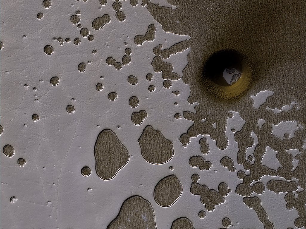 The HiRISE camera on NASA's Mars Reconnaissance Orbiter captured this unusual crater or pit on the surface of Mars. Frozen carbon dioxide gives the region its unique