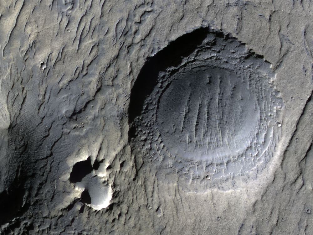 This impact crater is in Noachis Terra on Mars. Most craters have a plain bowl shape, but this one is being shaped by surface processes. This crater is 300 m (984 ft) in diameter. Image Credit: NASA/JPL/UofArizona