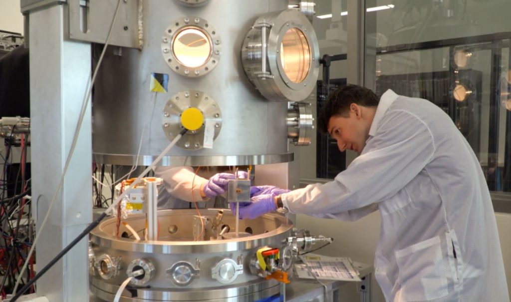 Julian Hammerl makes adjustments to a metal cube representing a derelict spacecraft inside the ECLIPS facility. Image Credit: Nico Goda/CU Boulder