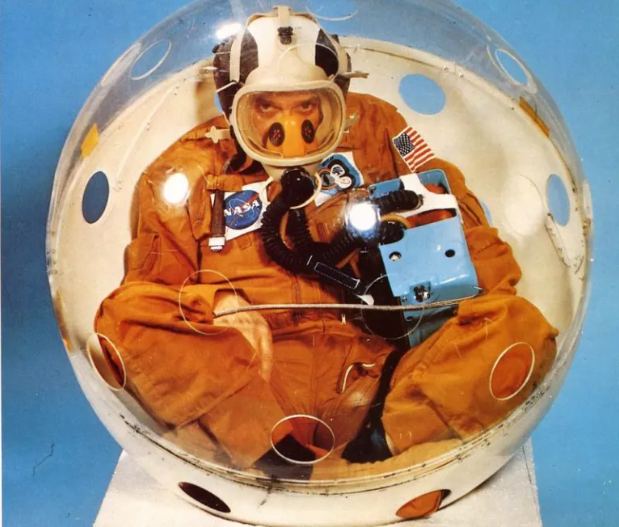 This image shows a demonstration version of the PRE, complete with breathing holes. The astronaut inside doesn't look too happy, and for some reason, is wearing an orange Skylab uniform. Image Credit: NASA