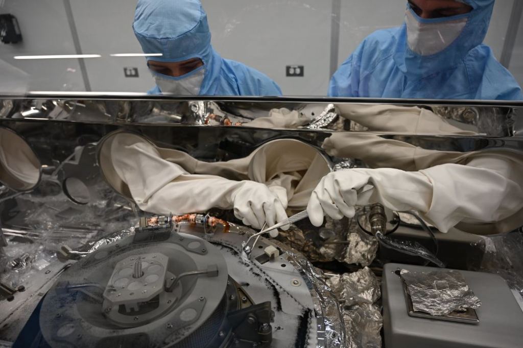 Processing Bennu's sample is a meticulous process that took years of preparation. In this image, astromaterials processors Mari Montoya, left, and Curtis Calva, right, use tools to collect asteroid particles from the base of the OSIRIS-REx science canister. Image Credit: NASA
