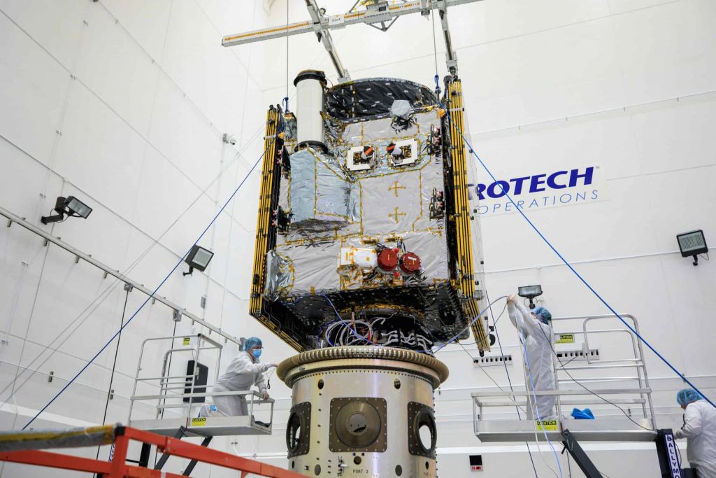 This image shows the Psyche spacecraft in a clean room. The DSOC is the silver tube extending toward the top of the image. Image Credit: NASA.