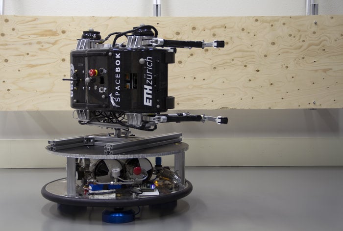 SpaceBok mounted on its side at ORBIT. By bouncing off the plywood walls with its legs, it was able to simulate performance on extremely low-gravity objects like asteroids. Image Credit: ETH Zurich/ZHAW Zurich