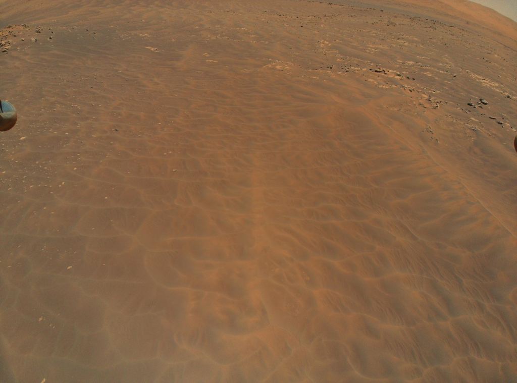 Ingenuity's view of the Séítah dune field on it's ninth flight. Part of the helicopter's landing gear can be seen on the left side of the screen.