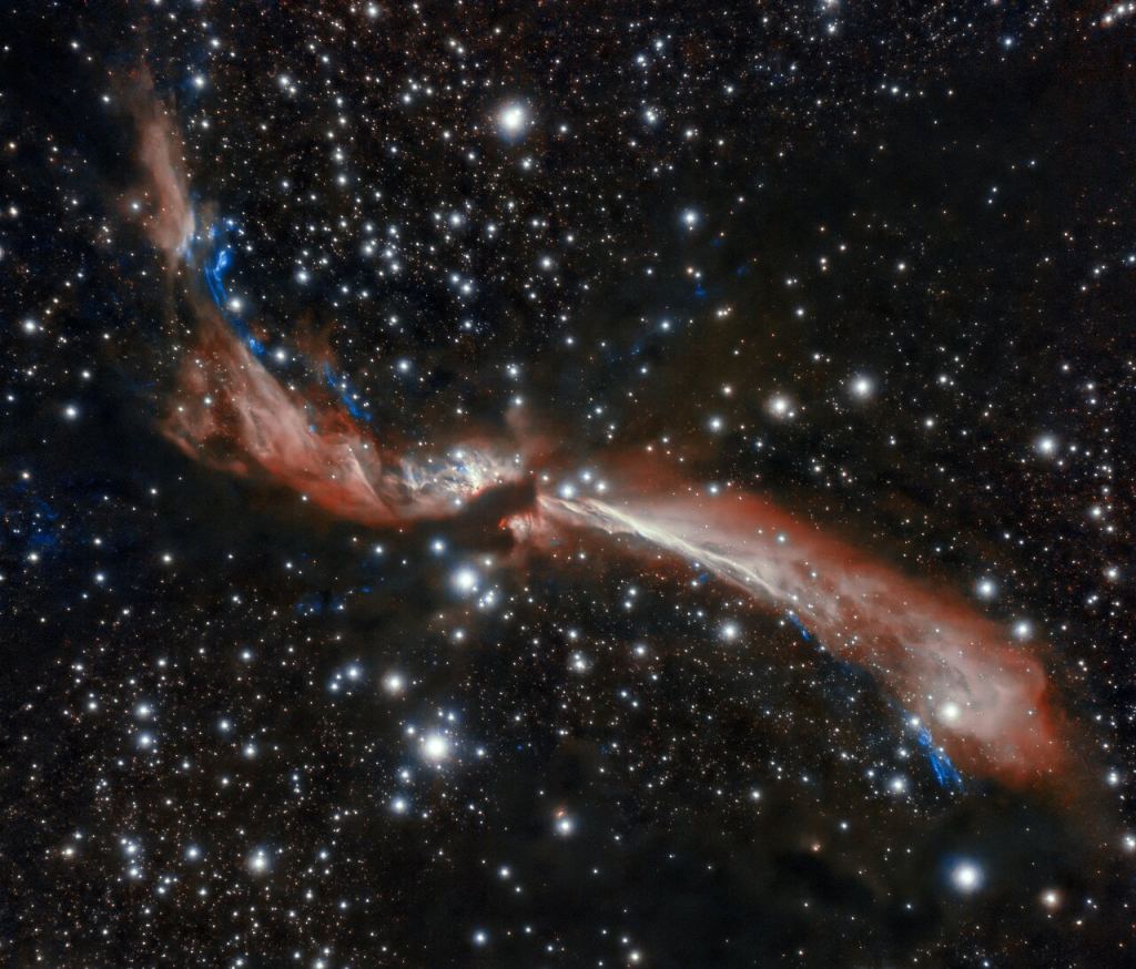 The sinuous young stellar jet, MHO 2147, meanders lazily across a field of stars in this image captured from Chile by the international Gemini Observatory, a Program of NSF's NOIRLab. The stellar jet is the outflow from a young star that is embedded in an infrared dark cloud. Astronomers suspect its sidewinding appearance is caused by the gravitational attraction of companion stars. These crystal-clear observations were made using the Gemini South telescope’s adaptive optics system, which helps astronomers counteract the blurring effects of atmospheric turbulence. Image Credit: International Gemini Observatory/NOIRLab/NSF/AURA
