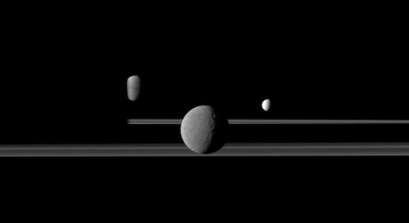 The Cassini spacecraft observes three of Saturn's moons set against the darkened night side of the planet. Credit: NASA/JPL/Space Science Institute