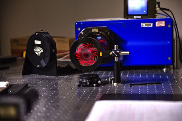 This image shows how the photon sieve brings red laser light to a pinpoint focus on its optical axis, but produces exotic diffraction patterns when viewed from the side. Credits: NASA/W. Hrybyk