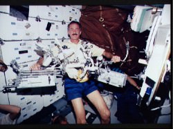 Astronaut Jeffrey A. Hoffman, floating in the forward middeck area,   displays tools used in the five space walks on STS-61.  Credit: NASA