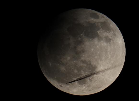 Airliner flies through partial eclipse! On April 25, 2013, around 10:10 PM local time, the partial Lunar eclipse was at its maximum. The Moon only traveled 1,3% into the central Earth shadow (umbra). The event was visible from Europe, Asia and Australia. Canon EOS 600D on 130 mm (f/7,1) triplet Apo-refractor settings: 1/200 exposure at ISO 100.  Credit and copyright:  Philip Corneille – FRAS (Belgium).