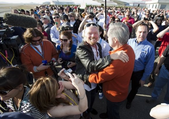 Sir Richard Branson hugs designer Burt Rutan as they are surrounded by employee's of Virgin Galactic, The SpaceShip Company and Scaled Composites watch as Virgin Galactic's SpaceShip2 streaks across the sky under rocket power, its first ever since the program began in 2005. Burt's wife Tonya Rutan is at right taking their photo. The spacecraft was dropped from its "mothership", WhiteKnight2 over the Mojave, CA area, April 29, 2013 at high altitude before firing its hybrid power motor. Virgin Galactic hopes to become the first commercial space venture to bring multiple passengers into space on a regular basis.