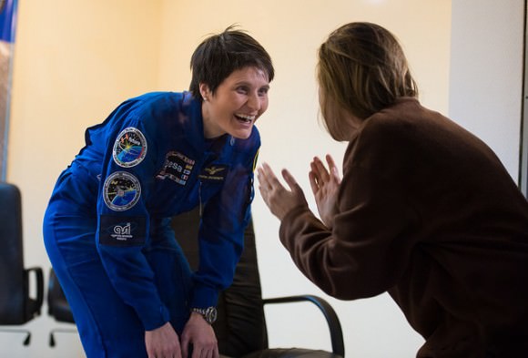 Prior to the launch of Expedition 42 in November 2014, Samantha Cristoforetti (left, European Space Agency) speaks with a loved one through the glass at a pre-launch press conference. Credit: NASA/Aubrey Gemignani