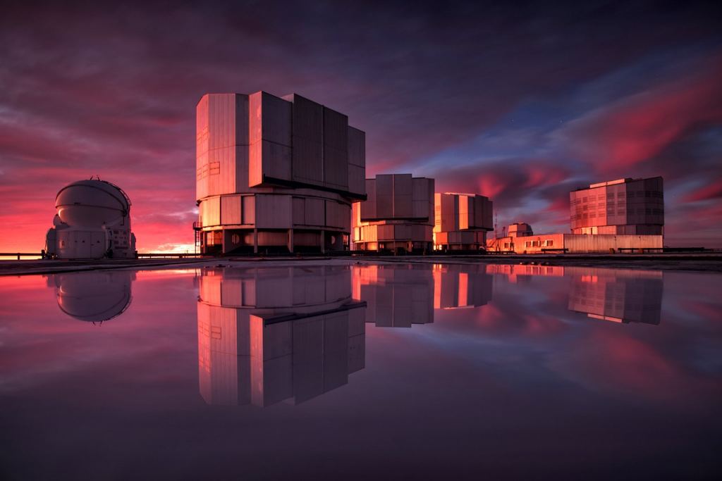ESO's Very Large Telescope (VLT) recently received an improved addition to its suite of advanced instruments.  On May 21, 2019, the newly modified VISIR (VLT Imager and Spectrometer for Mid-Infrared) instrument made its first observations since being modified to aid in the search for potentially habitable planets in the Alpha Centauri system, the closest star system of the earth.  This stunning image of the VLT is painted in the colors of the sunset and is reflected in the water on the platform.  While inclement weather at Cerro Paranal is unfortunate for the astronomers who use it, it allows us to see ESO's flagship telescope in a whole new light.  Image Credit: ESO / VLT