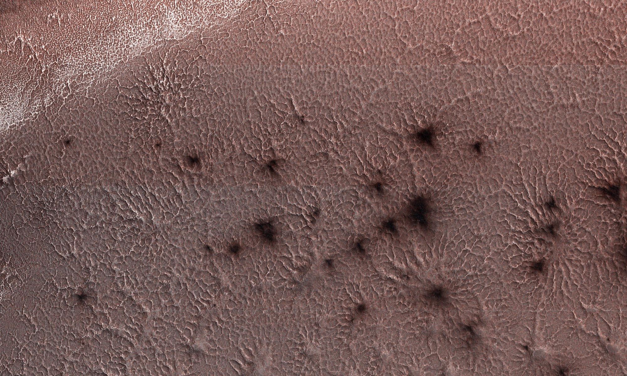 NASA's Mars Reconnaissance Orbiter, acquired May 13, 2018 during winter at the South Pole of Mars, shows a carbon dioxide ice cap covering the region and as the sun returns in the spring, "Mars spiders" begin to emerge from the landscape. Credit: NASA