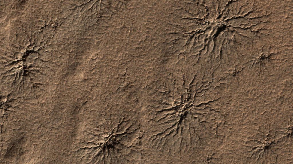 Since discovering them in 2003 via images from orbiters, scientists have marveled at these Mars spiders sprawled across the southern hemisphere of Mars. No one is entirely sure how these geologic features are created but lab simulations may provide clues. Credit: NASA/JPL-Caltech/University of Arizona