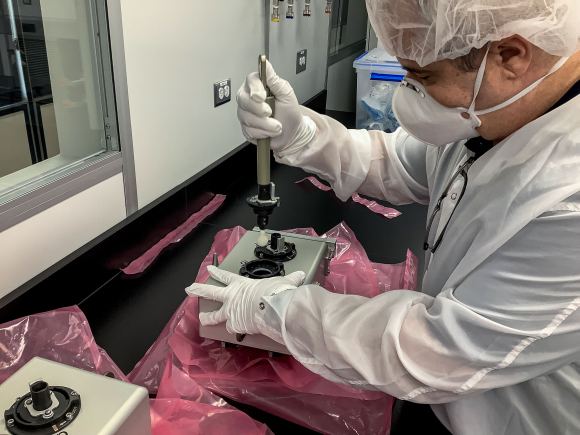 A member of the ISS External Microorganisms payload development team demonstrates removing a swab from the sampling caddy.